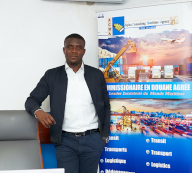 Homme accoudé à un bureau, kakemono ACMA à côté de lui